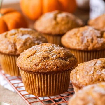 Sourdough pumpkin muffins topped with coarse sugar on a cooling rack.