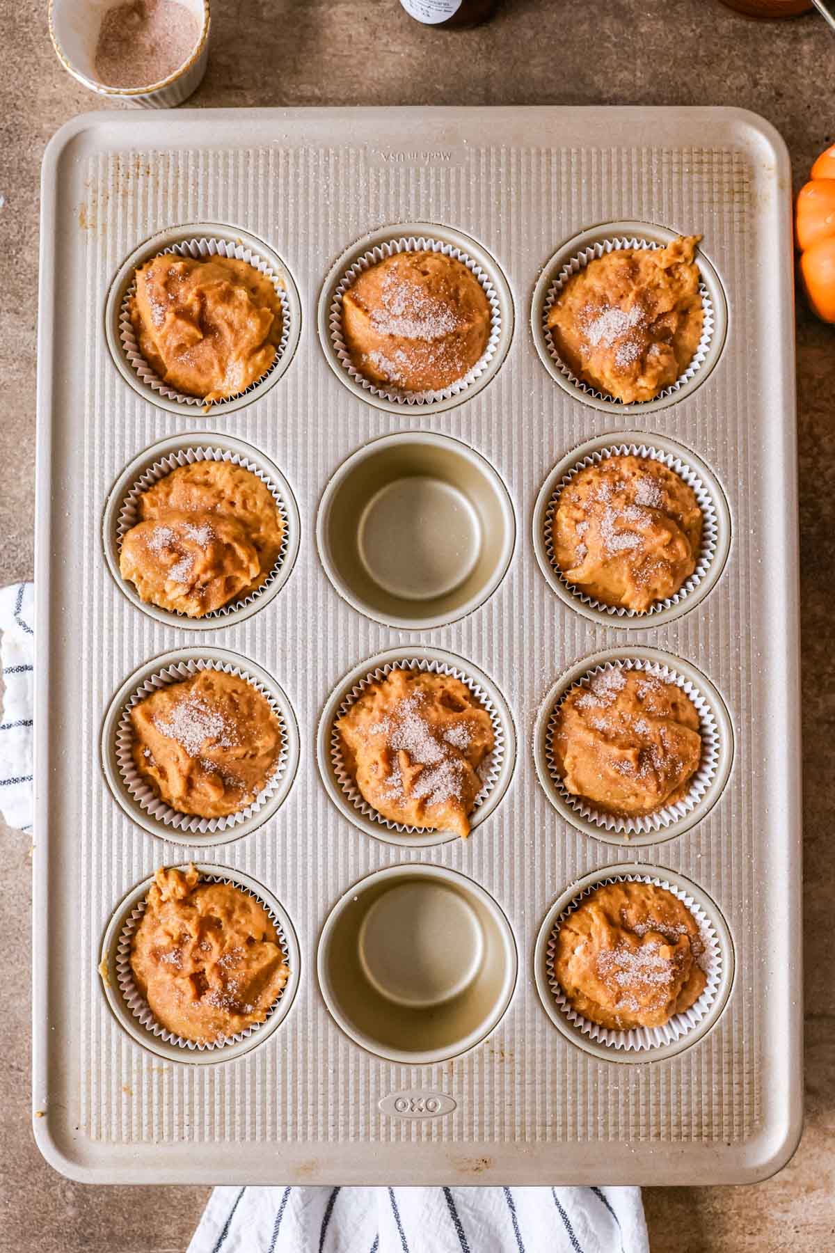 Overhead view of a muffin pan with sourdough pumpkin muffin batter inside before baking.