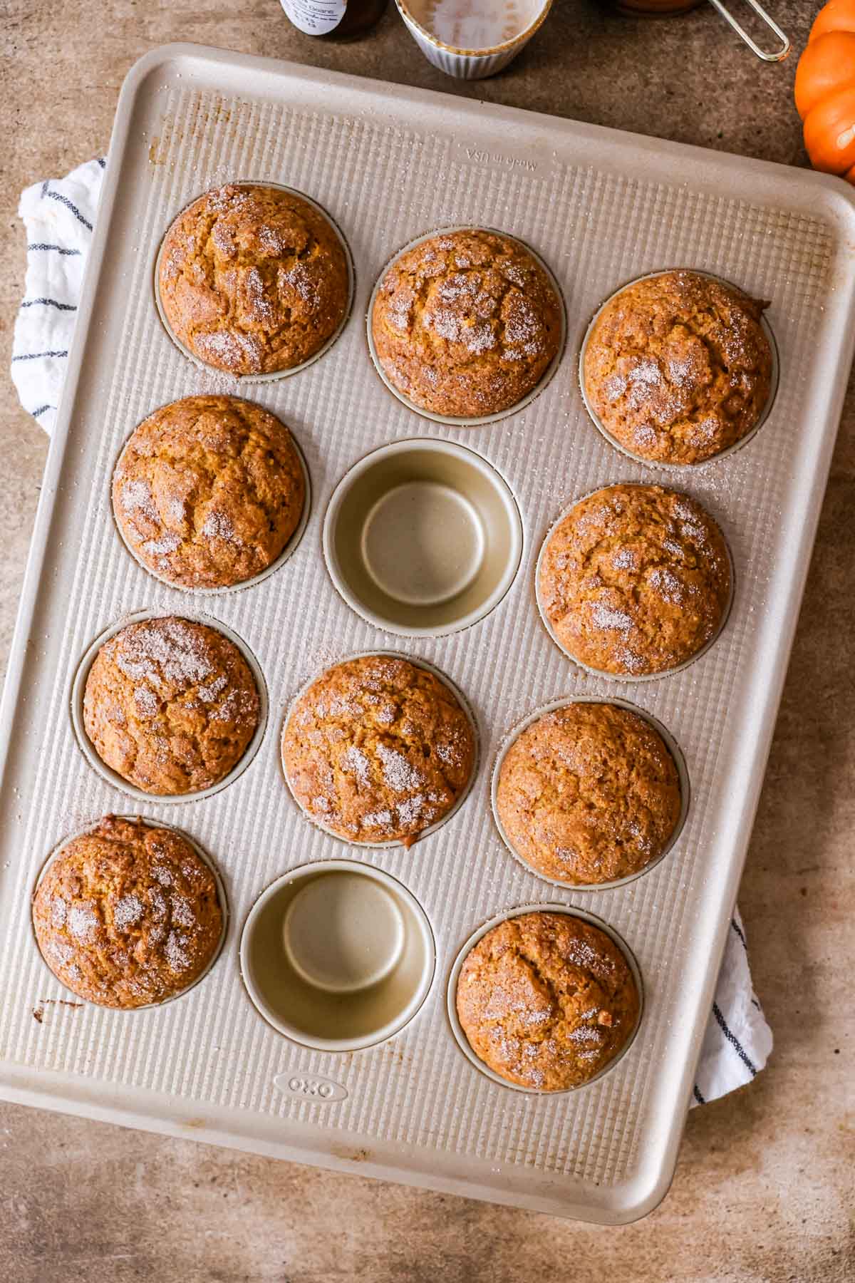 Overhead view of a muffin pan with sourdough pumpkin muffin batter inside after baking.