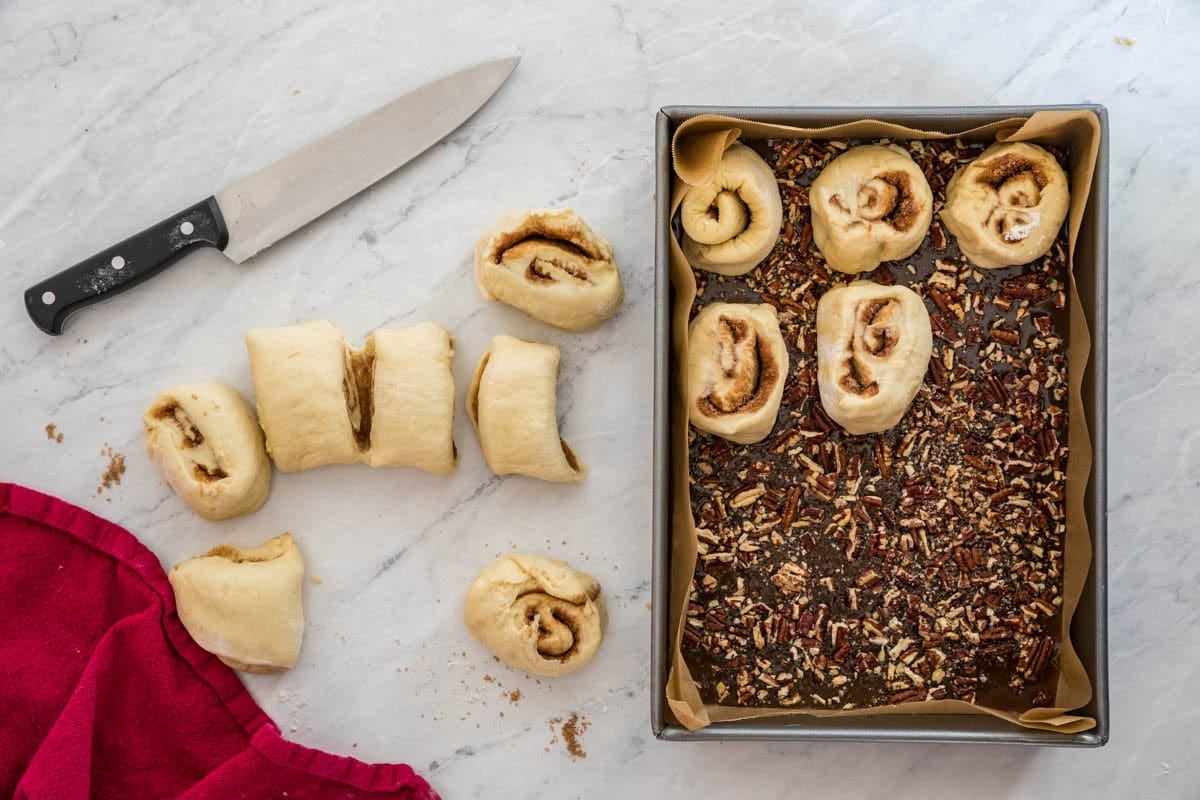 Cut sticky buns being arranged into a 9x13 baking pan.