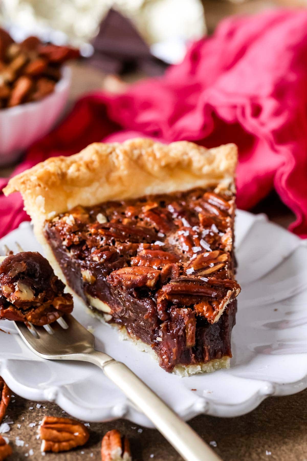 Bite missing from a slice of pie made with pecans and chocolate.