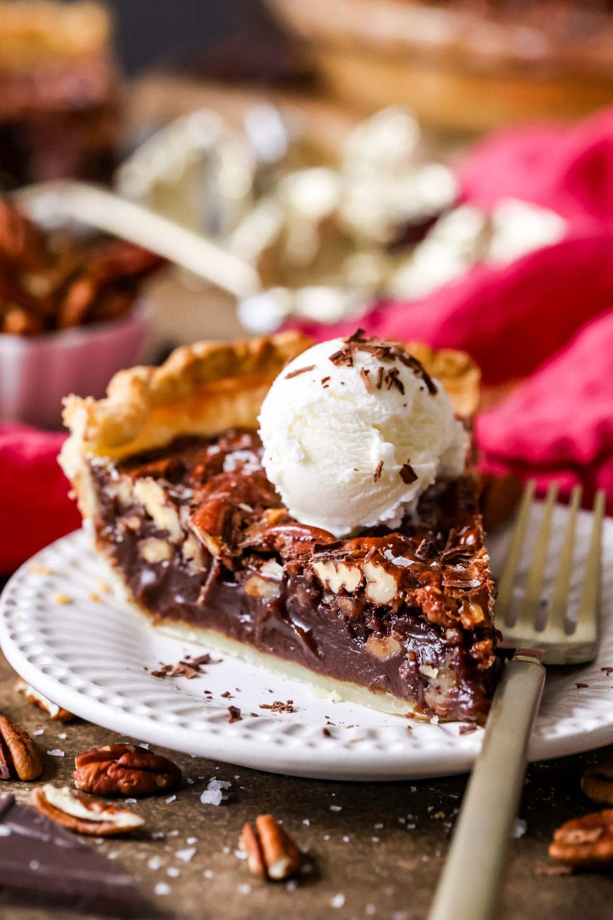Slice of chocolate pecan pie topped with a scoop of ice cream.