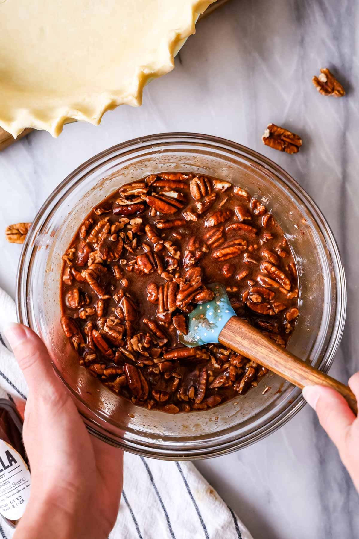 Overhead view of pecans being stirred together with corn syrup, chocolate, and melted butter.
