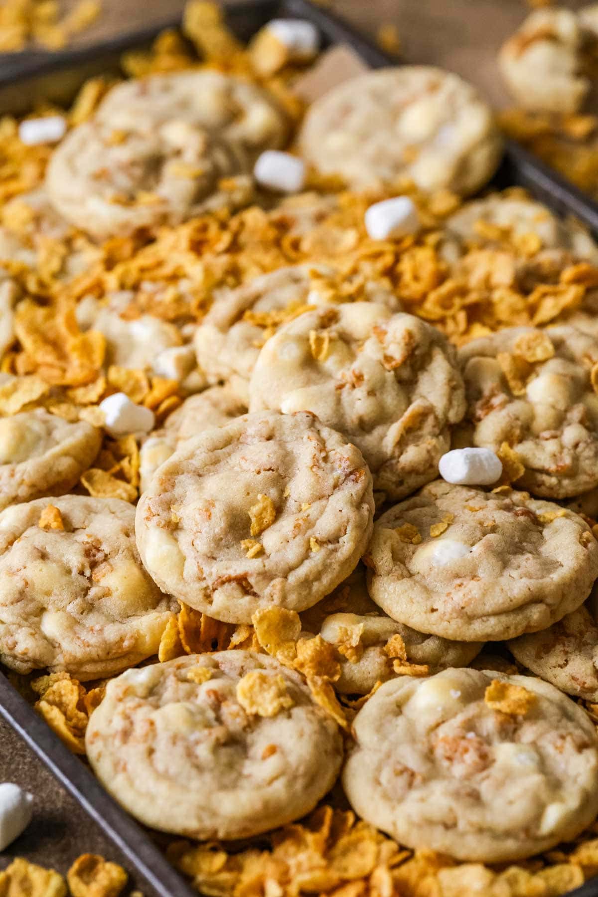 Cornflake cookies surrounded by cornflakes and mini marshmallows.